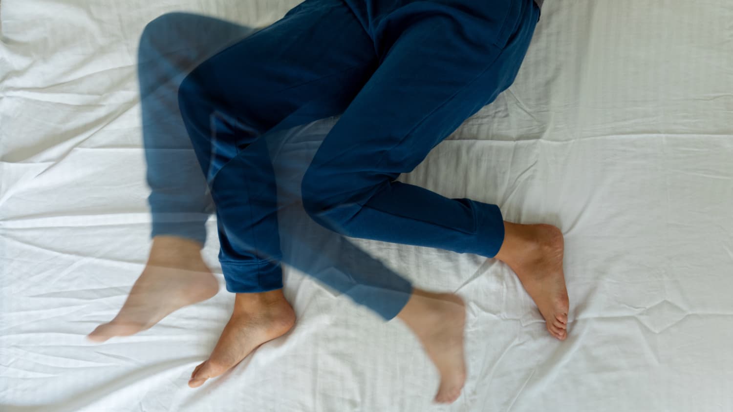 A woman with restless legs syndrome (RLS) tosses and turns in bed because the discomfort makes it  hard to sleep.